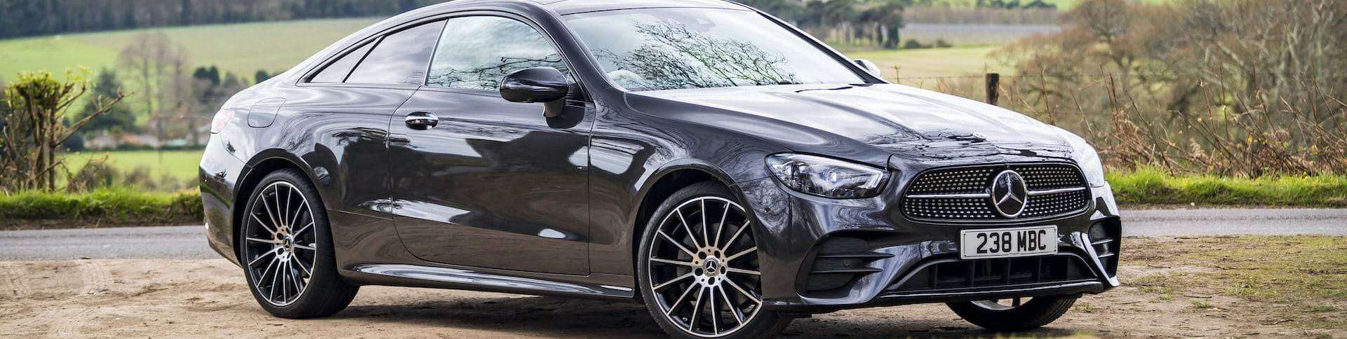Un coupé noir élégant garé au bord d'une route en Côte d'Ivoire, mettant en valeur l'élégance et le design sportif sur fond de campagne pittoresque.